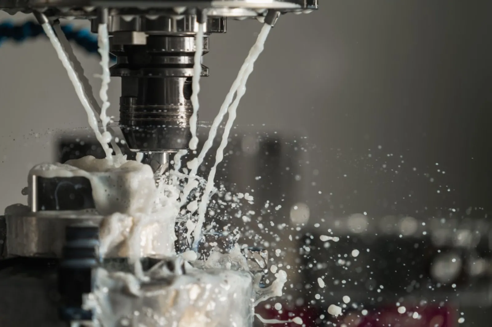 Machine CNC usinant une pièce métallique avec liquide de coupe.